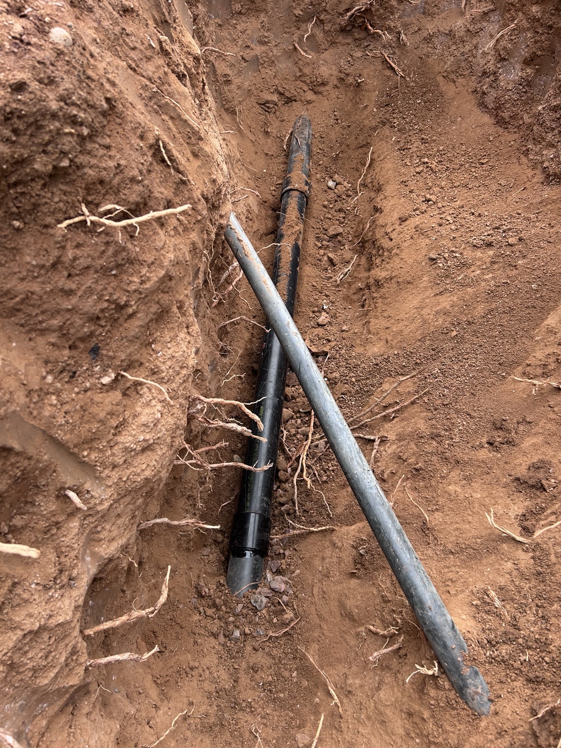 Close-up of exposed underground pipe and connections